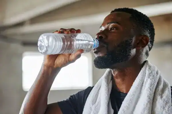 Image of man drinking water to improve hydration Cambridge after work out.